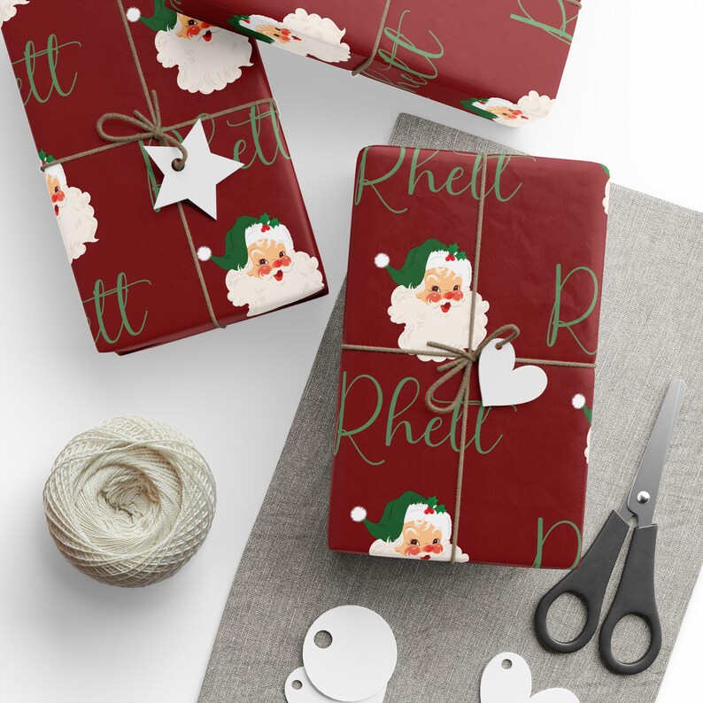 May include: Red wrapping paper with a repeating pattern of vintage Santa Claus faces and the name "Rhett" written in green cursive.