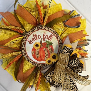 Traditional fall, pumpkin themed cheetah print door decor, sunflowers and pumpkin decor, yellow and orange wreath welcomes the fall season