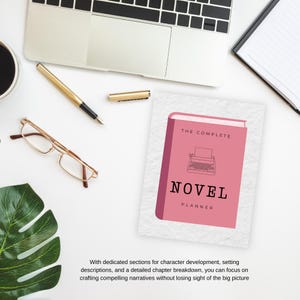 Op de afbeelding: Een roze boek met de titel "The Complete Novel Planner" en een illustratie van een typemachine. Het boek ligt op een wit oppervlak met een laptop, een pen en een bril.