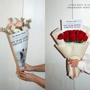 Może przedstawiać: Dwa bukiety kwiat&oacute;w owinięte w papier. Jeden zawiera r&oacute;żowe i białe kwiaty, drugi czerwone r&oacute;że. Papier jest zadrukowany napisem "The Lover Times" i tekstem "ONE YEAR DOWN, FOREVER TO GO!"