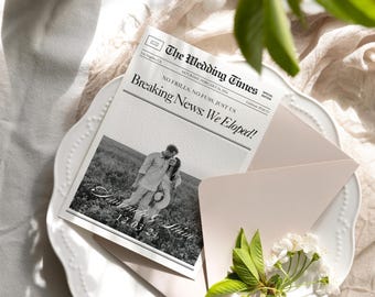May include: A wedding announcement featuring a newspaper-style design with the headline "Breaking News: We Eloped!" The announcement includes a black and white photo of a couple and the date 12.03.24. The announcement is placed on a white plate with a pink envelope and floral accents.