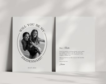 May include: A black and white photo of two women smiling. The text "Will you be my bridesmaid?" is written in a circle around the photo. The date "09.07.2024" is written below the circle. A handwritten note on a white background says "Dear Amelia, From the moment we became friends, you've added joy, laughter, and love to my life. As I step into this new chapter of love and commitment, I can't imagine it without you. Will you stand by my side as I go on this beautiful journey? With all my love, Jessica"
