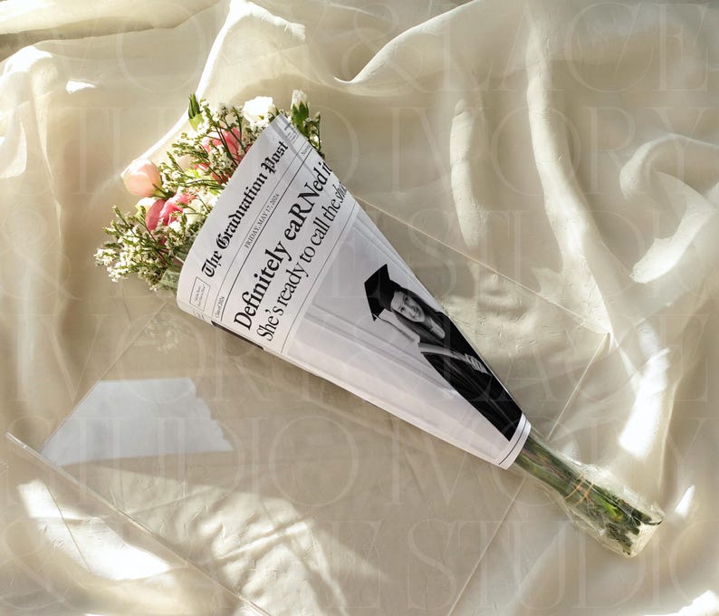 May include: A bouquet of pink and white flowers wrapped in newspaper. The newspaper reads "The Graduation Post" with the headline "Definitely eARNed it." A photo of a graduate is also visible.
