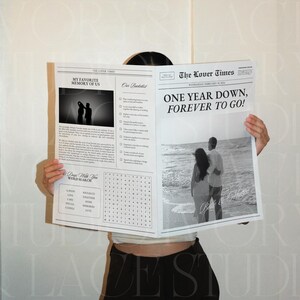 Może przedstawiać: Czarno-biała gazeta z nagł&oacute;wkiem "ONE YEAR DOWN, FOREVER TO GO!" trzymana przez osobę. Gazeta zawiera zdjęcia i tekst, w tym wyszukiwanie sł&oacute;w i słowa "MY FAVORITE MEMORY OF US."