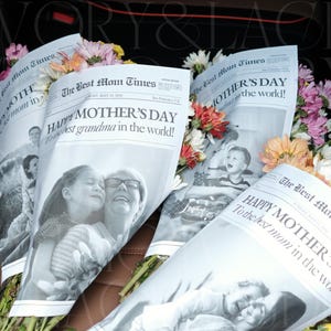 May include: Bouquets of colorful flowers wrapped in newspaper-style paper. The paper reads "Happy Mother's Day" and features black and white photos. The flowers include pink, white, orange, and yellow blooms.