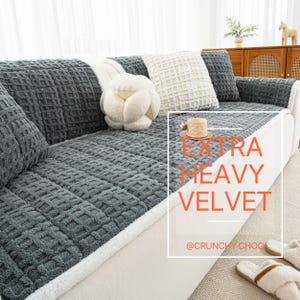 May include: A gray velvet sofa cover with a textured geometric pattern. The cover is draped over a white sofa, with matching pillows and a decorative white pillow. The text "EXTRA HEAVY VELVET" is visible.