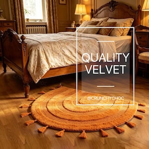 May include: An orange, semi-circular rug with concentric circles and tassels. The rug is made of a soft material and is placed on a wooden floor in front of a bed. The text "QUALITY VELVET" is displayed in the image.