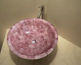 Pode incluir: Uma pia de banheiro rosa feita de quartzo rosa com uma torneira cromada.