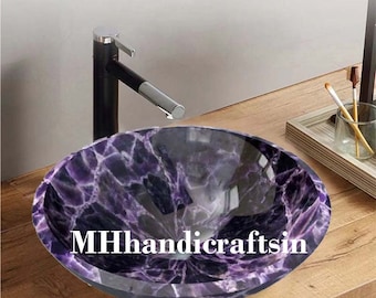 May include: A round purple and black marble bathroom sink with a black faucet. The sink is on a wooden countertop.