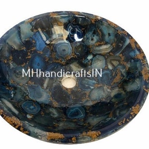 May include: A round blue agate stone sink with gold accents. The sink is made of natural stone and has a unique, organic pattern.