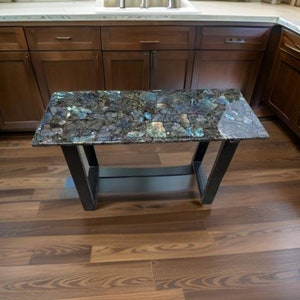 May include: A black metal table with a dark blue and green granite top. The table has a shelf underneath the top.