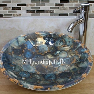 May include: A round blue and gold agate stone sink with a polished finish. The sink is made of natural stone and has a unique pattern. The sink is perfect for a modern bathroom.