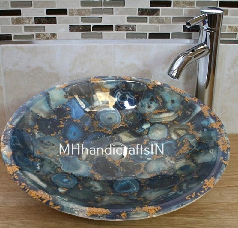 May include: A round blue and gold agate stone sink with a polished finish. The sink is made of natural stone and has a unique pattern. The sink is perfect for a modern bathroom.