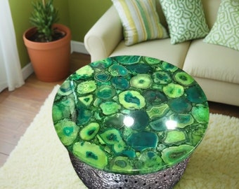 May include: A round green agate coffee table with a silver base. The table top is made of polished green agate with a variety of patterns and textures.
