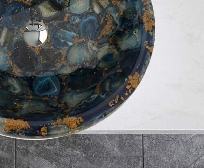 May include: A round, blue and gold sink with a unique agate design. The sink has a drain hole in the center.