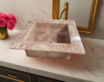Può includere: Un lavabo da bagno quadrato in marmo rosa e bianco con una finitura liscia e lucida.