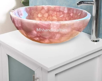 Pode incluir: Uma pia de banheiro de pedra natural rosa e branca com uma bancada branca e uma torneira cromada. A pia é feita de pedra natural e tem um formato único e orgânico. A pia é perfeita para um banheiro moderno.