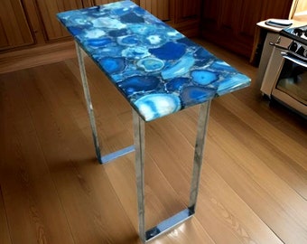 May include: A modern console table with a blue agate top and a chrome metal frame. The table is standing on a wooden floor.