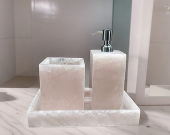 May include: A white marble bathroom set with a soap dispenser and a toothbrush holder. The set is on a white marble tray.