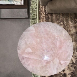 May include: A round pink rose quartz table top with a polished finish. The table top is made of natural stone and has a unique pattern.