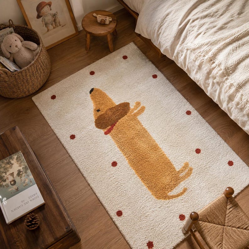 May include: A rectangular area rug with a cream-colored background featuring a repeating pattern of small red dots and a central graphic of a tan dachshund dog with a dark brown ear and a red collar, rendered in a textured, tufted pile finish.