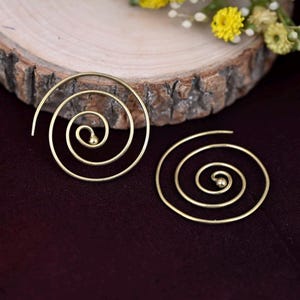 May include: A pair of gold spiral hoop earrings. The earrings are made of thin wire and have a simple, elegant design.