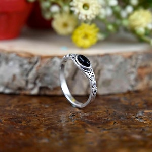 Op de afbeelding: Een zilveren ring met een zwarte ovale edelsteen in een delicaat filigraan ontwerp.