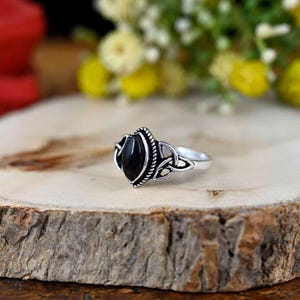 May include: A silver ring featuring a black gemstone set within a Celtic knot design.