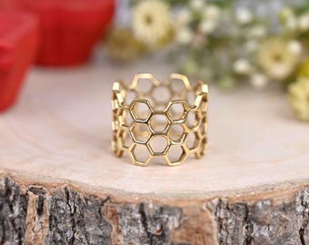 May include: A gold honeycomb ring with a textured design. The ring is made of metal and has a wide band.
