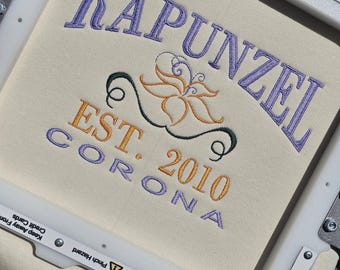 Könnte beinhalten: Nahaufnahme eines weißen Stoffes mit lila Stickerei, die "Rapunzel Est. 2010 Corona" lautet. Die Stickerei enthält auch ein stilisiertes Blumenmuster.