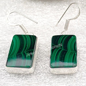 May include: A pair of silver earrings with green malachite stone rectangular drops. The earrings have a spring-loaded hook closure.