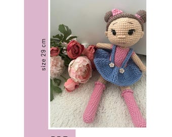May include: Crochet doll pattern PDF for a 29 cm tall doll with brown hair, pink dress, blue overalls, and pink shoes. The pattern is called "Doll Julia Photo Pattern" and is available for download. The image also includes a logo for "Lovely Crochet".