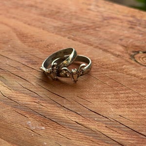 May include: Two silver-toned metal rings, each featuring a small, detailed bat motif centered on the band. The rings have a slightly oxidized or darkened finish in the recessed areas, highlighting the wings and ears of the bat design.