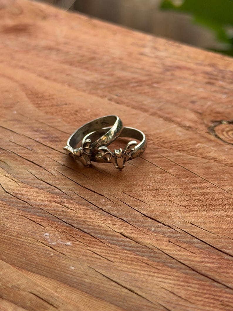 May include: Two silver-toned metal rings, each featuring a small, detailed bat motif centered on the band. The rings have a slightly oxidized or darkened finish in the recessed areas, highlighting the wings and ears of the bat design.