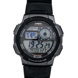 Puede incluir: Un reloj digital Casio negro con una esfera plateada. El reloj tiene una función de hora mundial, una batería de 10 años y es resistente al agua hasta 100 metros. La esfera del reloj muestra la hora, la fecha y el día de la semana. El reloj tiene una correa negra y un bisel plateado.