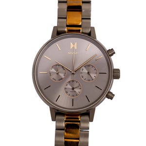 May include: A silver and gold toned watch with a chronograph and day of the week display. The watch face has a silver background with black markings and a rose gold coloured logo that says "MVMI".