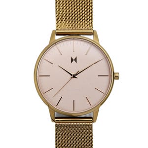 May include: Gold-coloured wristwatch with a mesh strap. The watch face is a pale pink with black hands and minimal hour markers. The watch case is round and has a simple, elegant design. The strap is made of a fine, woven metal.