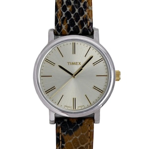 Peut inclure: Une montre Timex argentée avec un cadran blanc et des index romains noirs. La montre a un bracelet en cuir brun et noir.