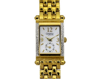 May include: A gold-tone Caravel by Bulova watch with a white face and diamond accents. The watch has a square face and a gold-tone metal band.
