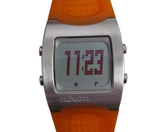 Reloj deportivo digital Nixon con pantalla LCD y correa de silicona en tono plateado y naranja