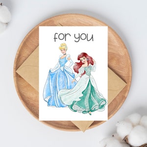 Pu&ograve; includere: Un biglietto d'auguri con il testo "for you" stampato sul davanti. Il biglietto presenta un'illustrazione di Cenerentola e Ariel di Disney.