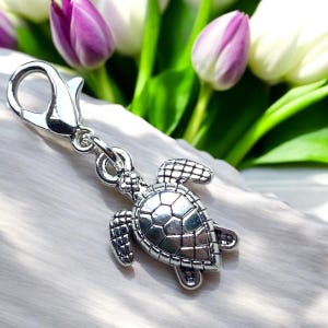 Peut inclure: Breloque en argent avec un motif de tortue de mer détaillé. Le breloque a un fermoir à ressort pour l'attacher à un sac, un porte-clés ou d'autres accessoires.