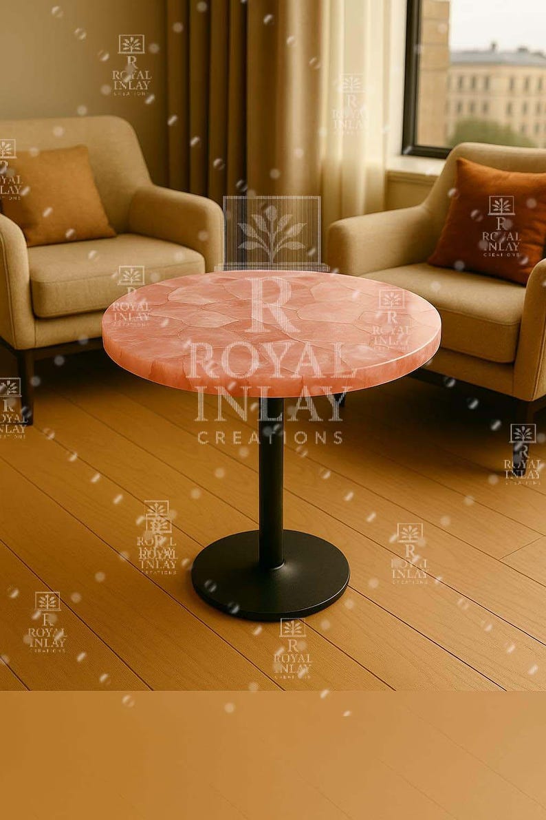 May include: A round, pink, table with a black metal base. The table top is made of natural stone with a unique, textured surface. The table is labeled "R Royal Inlay Creations".