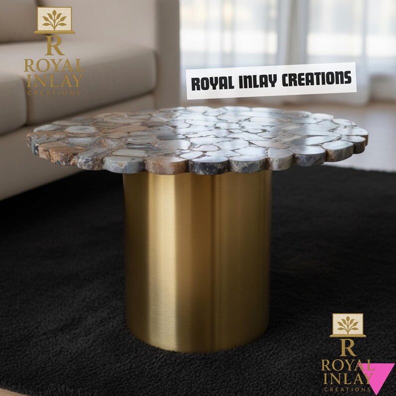 Puede incluir: Una mesa de centro redonda con una tapa de mosaico de piedra y una base cil&iacute;ndrica dorada. La parte superior est&aacute; hecha de piedras de forma irregular en tonos grises, marrones y blancos. El texto "ROYAL INLAY CREATIONS" est&aacute; visible.