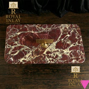 May include: Rectangular marble serving tray with a rich burgundy and cream veined pattern. Features a gold-toned handle and a small gold plaque with the text "ROYAL INLAY CREATIONS". The tray is set on a dark wood surface.
