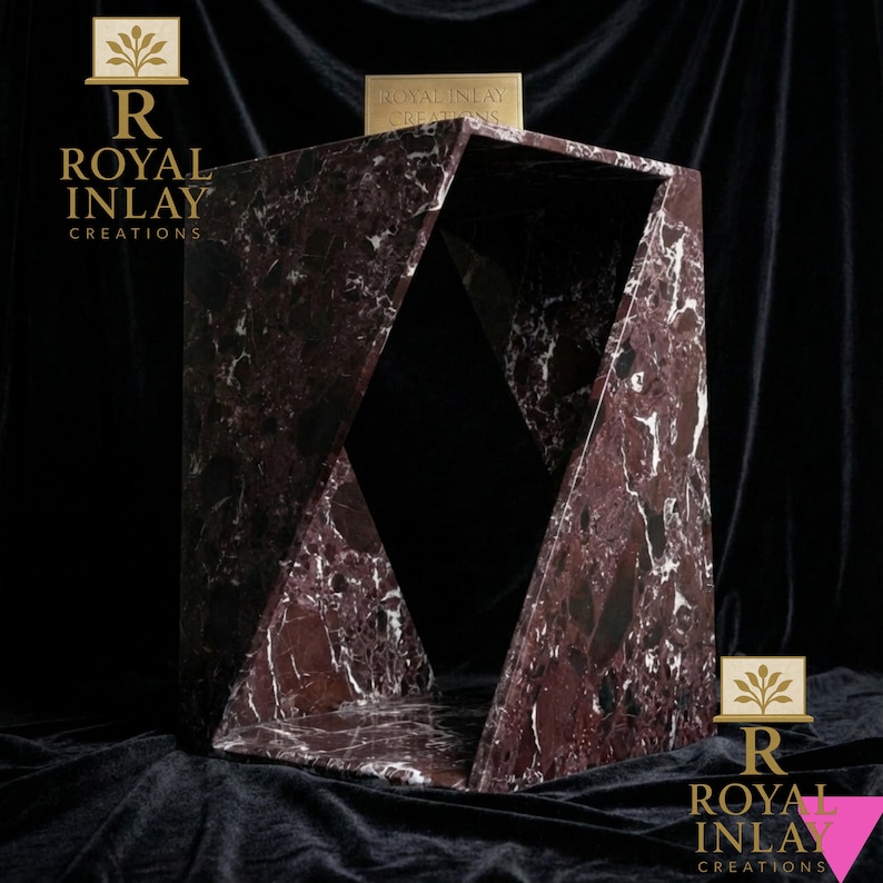 Puede incluir: Una mesa auxiliar geom&eacute;trica de m&aacute;rmol burdeos con vetas blancas. La mesa tiene un dise&ntilde;o &uacute;nico y abierto con lados angulados y una parte superior rectangular. Se muestra la marca "ROYAL INLAY CREATIONS".
