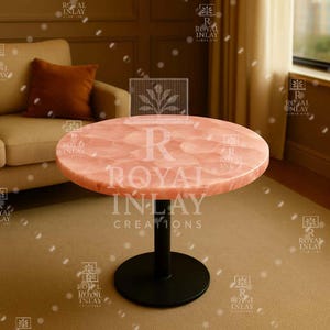 May include: A round, pink, marble table top with a black metal base. The table top has a unique, swirling pattern. The table is labeled "Royal Inlay Creations".