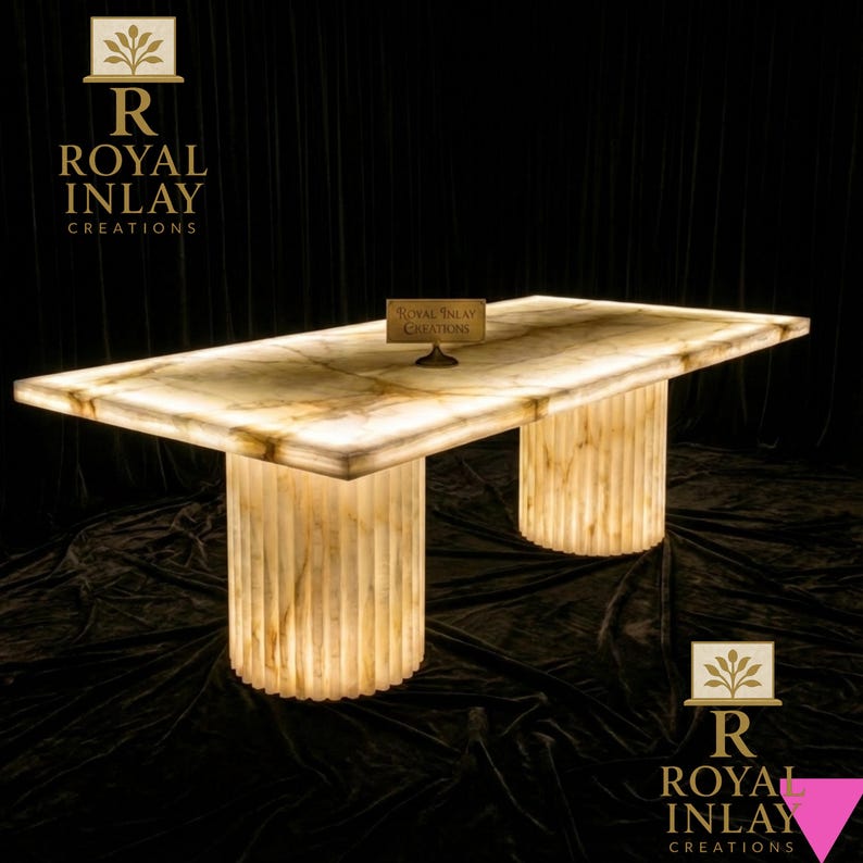 May include: A rectangular, illuminated onyx table with two cylindrical, fluted legs. The table's surface has a marble-like pattern. The table is branded with the text "Royal Inlay Creations".