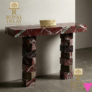 May include: A red marble console table with white and green veining. The table has a rectangular top and two stacked block legs. A small gold sign on the table reads "Royal Inlay Creations".
