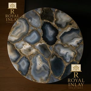 May include: A circular stone slab with a polished finish. It displays a mosaic pattern of blue, grey, and white sections, highlighted by gold-coloured accents. This item is likely for home decor.